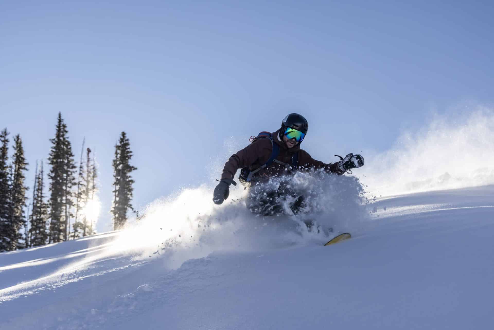 Snowboarder on a downhill run. Powder flying.